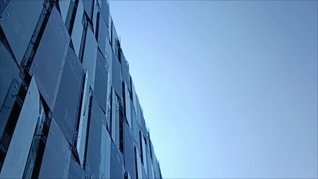 Modern architectural building facade with dark panel tiles looking up against clear blue sky, video stock clip of contemporary office exterior. Modern office building.