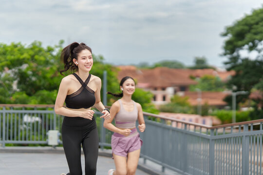 Asian women running outdoors on city bridge for morning jog and healthy fitness routine