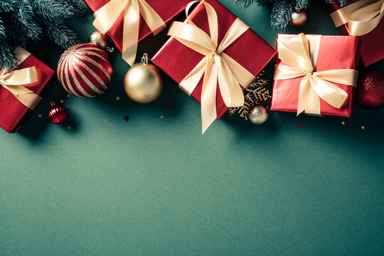 Red Christmas gifts and golden baubles top border on green background. Vintage, retro style.