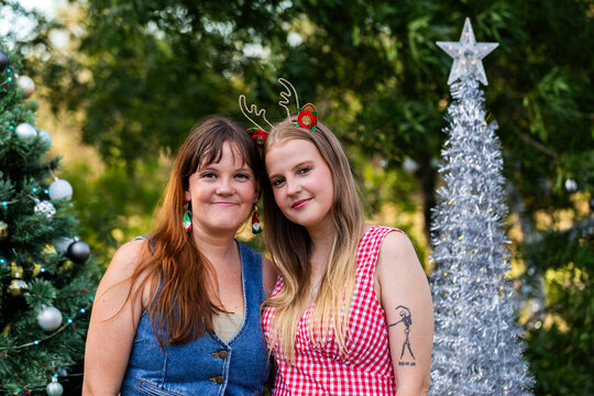 Portrait of two smiling sisters in their twenties together outside at Christmas time
