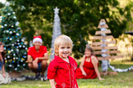 Preschooler boy portrait at Christmas with his family watching