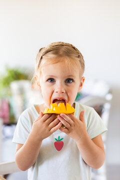 Little Australian girl eating a freshly cut mango fruit in kitchen at home