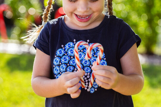 Child making heart shape with candy cane lollies at Christmas outdoors