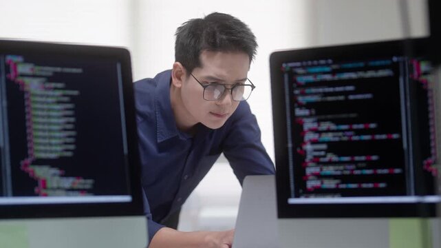 Programmer Coding Between Computer Monitors in Modern Office