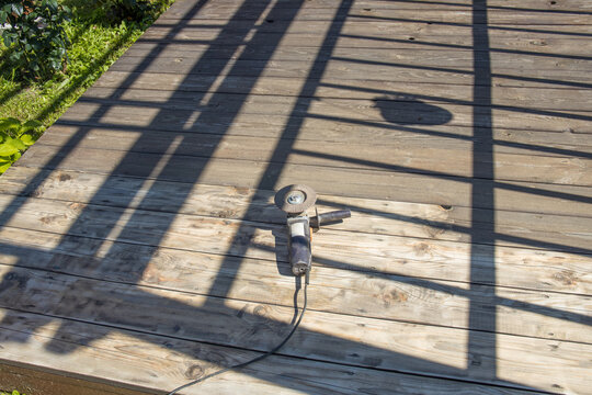 Drill sits idle on wooden deck, shadows cast by overhead structure