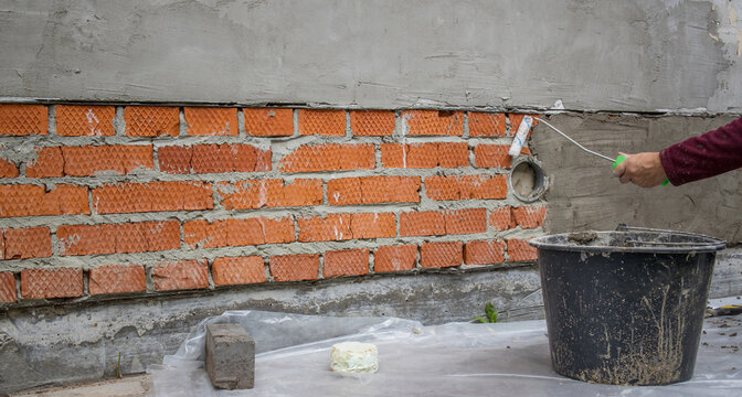 Person applies cement to brick wall with trowel