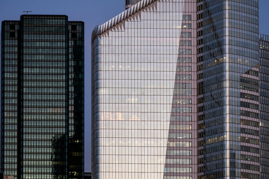 Modern office towers with glass facades and vertical grids form a dense urban skyline of contemporary high rise architecture under soft light