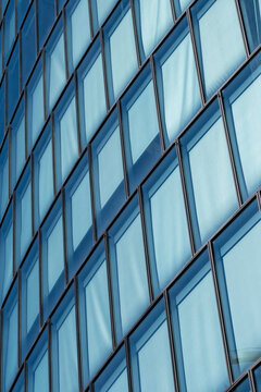 Blue glass windows and dark frames create a repeating geometric pattern across a modern office facade in a tight architectural detail