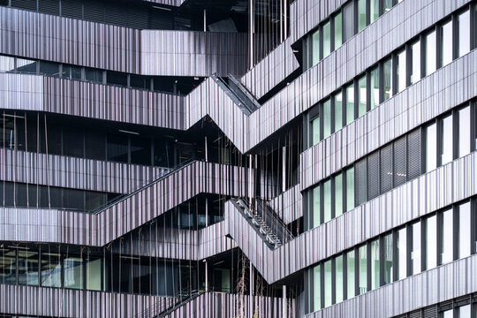 Angular modern facade with layered windows and zigzagging bands creating a dense geometric pattern across a contemporary office building exterior