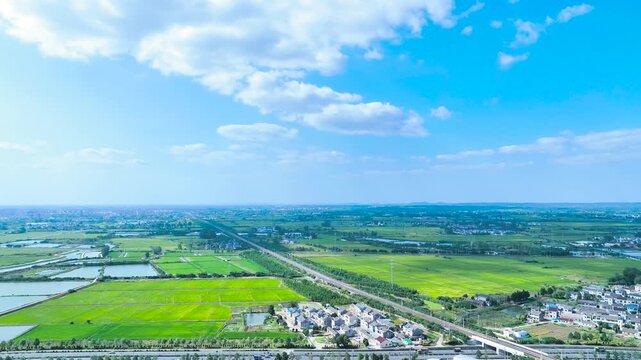 Aerial view of green farmland, canals and rural village under blue sky