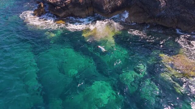 Aerial View of Male Freediver Swimming Through Turquoise Water by Rocky Coast at Voidokilia, Greece