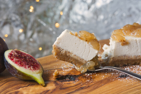 Fresh fig cheesecake slice with fig jam topping and ripe fresh fig on wooden board