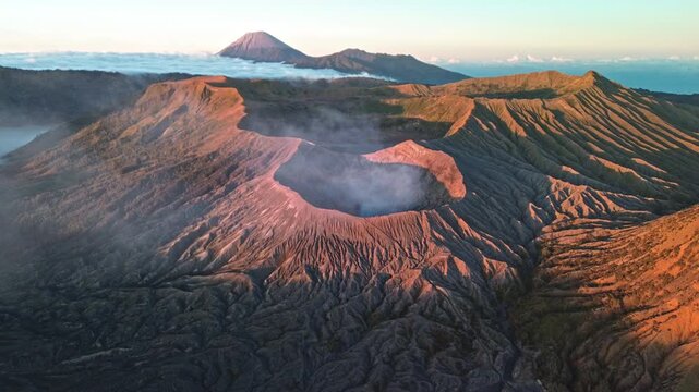 Drone orbit around the Mount Bromo crater in vibrant red and pink dawn light, revealing the smoking crater, surrounding volcanic landscape and Tengger caldera, Indonesia