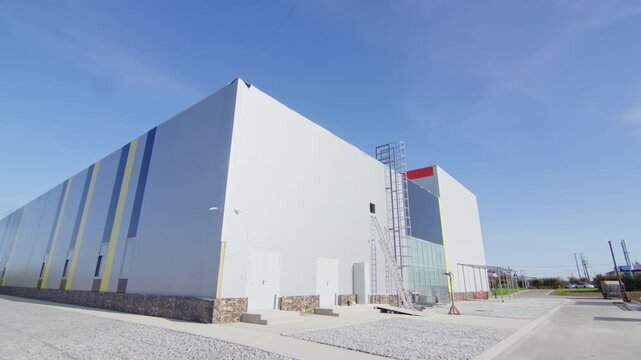 Commercial facility exterior displays clean architecture with access doors. Landscaping gravel border long facade of logistics center