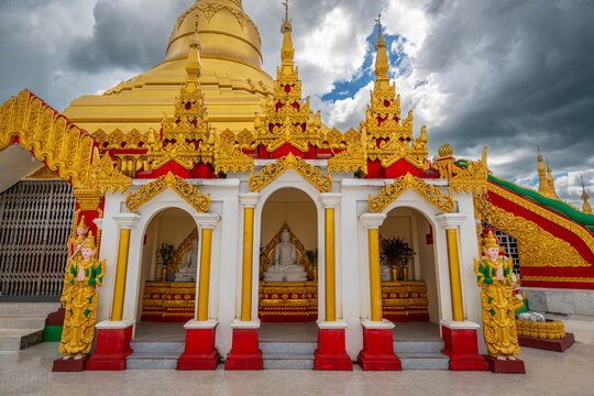 Pyay Tha Lin Aye Pagoda, known as Phra That Tagaw, features ornate golden shrines with white buddha statues positioned beneath a majestic golden stupa in Kayin State, Myanmar.