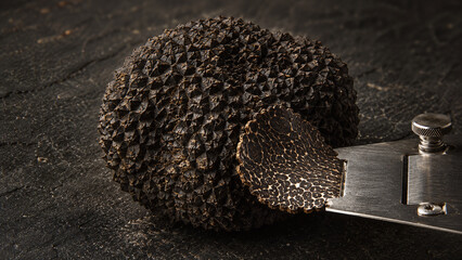 Fototapeta premium Black Périgord truffle extreme macro showing diamond-faceted warty exterior surface with interior marble slice revealing cream vein network on dark charcoal luxury food editorial