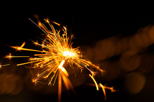 Sparkler glowing with sparks to celebrate new years eve with bokeh lights in background