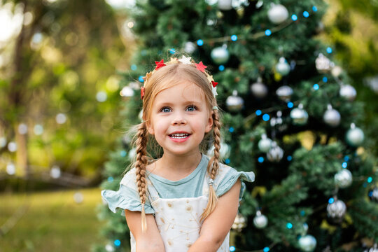 Girl looking upwards at Christmas time outdoors by decorated tree
