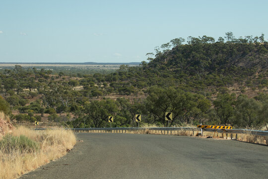Looking over a bend in the bitumen road to the outback landscape beyond