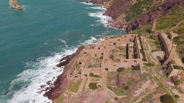 Historic Laveria Lamarmora Washing Plant Ruins On Rocky Coastline At Miniera Di Nebida In Sardinia, Italy. descending drone shot