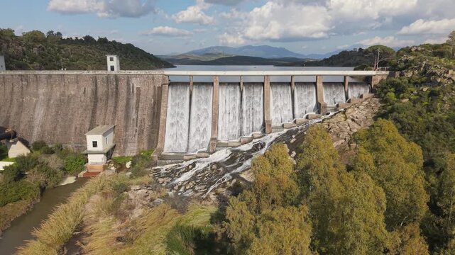 Water Flowing Over Concrete Dam At Lago Di Monte Pranu In Sardinia, Italy. drone sideways shot