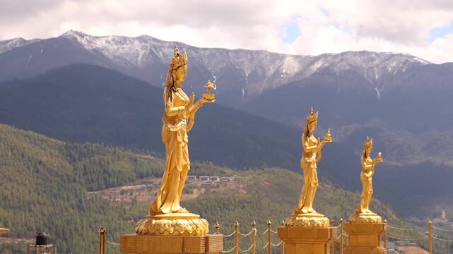 Golden Religious Bodhisattva Statues Against Himalayan Mountains in Thimphu, Bhutan