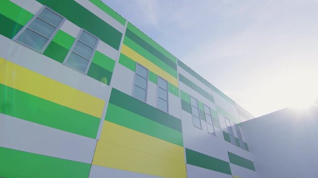 Multi-story wall paneling with vertical windows and open doorway. Stone cladding strip borders foundation below colorful facade panels