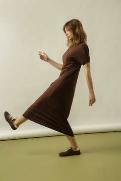 Fashion model wearing a brown cotton midi dress with matching brown sneakers, simple comfortable and stylish casual look