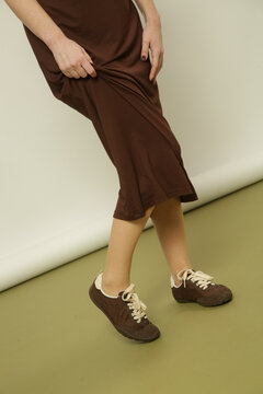 Fashion model wearing a brown cotton midi dress with matching brown sneakers, simple comfortable and stylish casual look
