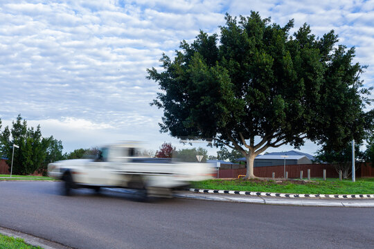 Blurred motion of a ute passing around a roundabout on overcast morning