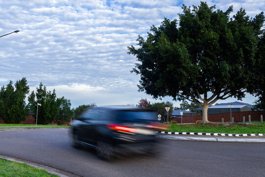 Blurred motion of a car passing around a roundabout on overcast morning
