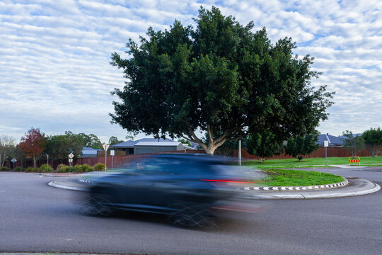 Blurred motion of a car passing around a roundabout on overcast morning