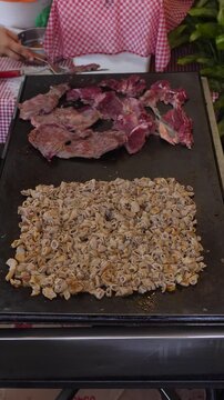 Pork tripe and beef cooking on a griddle at a Mexican taqueria