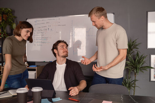 Team collaborating in a modern office with devices and whiteboard for planning