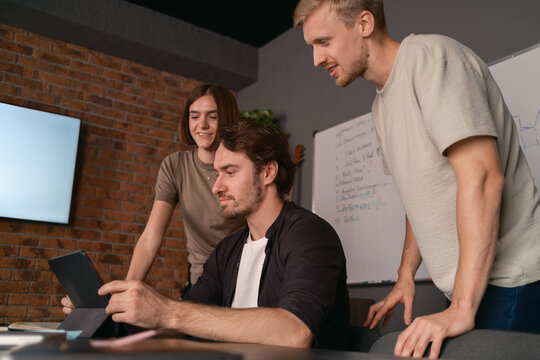 Coworkers collaborating on a project while using a tablet in shared workspace