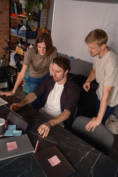 Team collaborating enthusiastically on a project at a modern workspace with creative tools