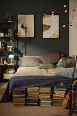 Cozy bedroom interior featuring stacks of books under bed and ukulele nearby, representing student lifestyle. Ideal for home decor and youth lifestyle marketing, vertical © DragonImages