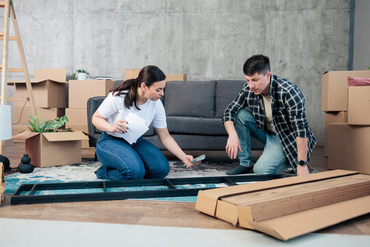 Young couple assembling furniture in new home living room