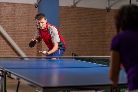 Male table tennis player serving against an opponent