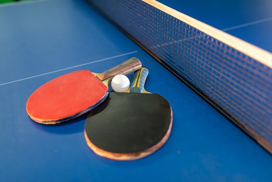 Table tennis paddles and ball lying on a blue table