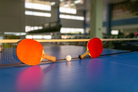 Two table tennis paddles resting against the net