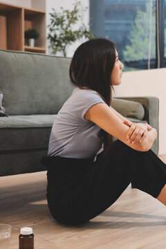 Young Asian woman sitting in bed and holding her head in pain with headache, feeling depressed 

and suffering