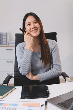 young woman is working on laptop in modern office environment, showcasing focused and productive atmosphere. She is dressed in professional white shirt, with coffee cup and small plant on table,