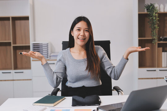 young woman is working on laptop in modern office environment, showcasing focused and productive atmosphere. She is dressed in professional white shirt, with coffee cup and small plant on table,
