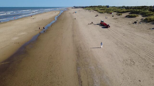 Drone shot looking along Mablethorpe beach in Lincolnshire, UK, a sandy beach beneath a blue sky