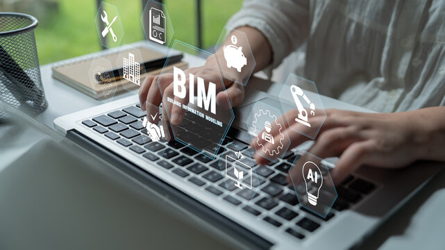 Young professional using laptop with holographic interface showcasing BIM concepts and digital icons in modern workspace to illustrate technology and innovation. Glyphic.
