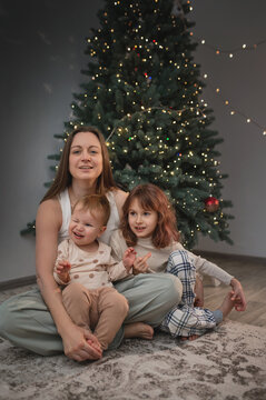  family of 2 children, mom are celebrating New Year's and Christmas under the Christmas tree at home, opening presents. A quiet, cozy family evening.