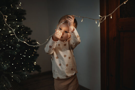 A small child touches electrical wires from a Christmas tree. Children without adult supervision. Electrical injuries, without parental supervision. Unpleasant incident on New Year's Eve.