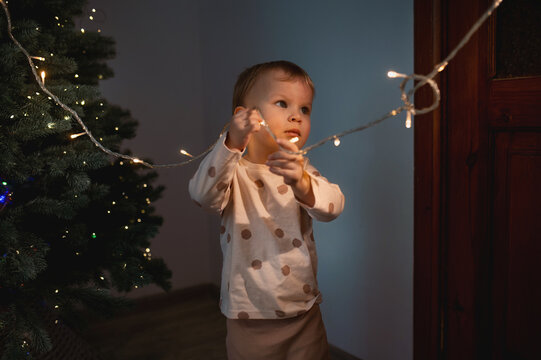 A small child touches electrical wires from a Christmas tree. Children without adult supervision. Electrical injuries, without parental supervision. Unpleasant incident on New Year's Eve.