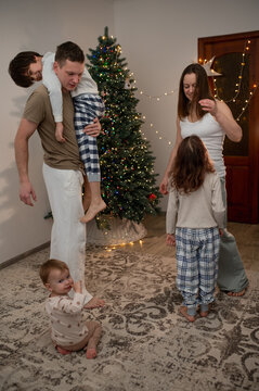 family of three children, mom and dad, are celebrating New Year's and Christmas near Christmas tree at home. A quiet, cozy family evening. Lifestyles family emotional portrait at home. Blurred